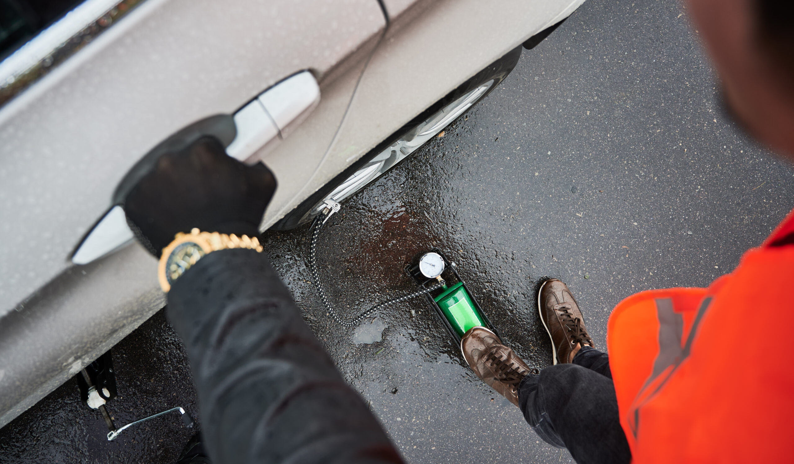 Auto mechanic inflating tire with air compressor on the street.